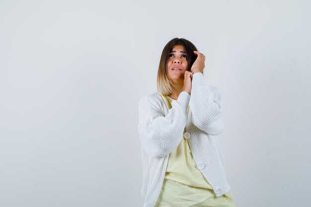 Young woman wearing a white cardigan being scared