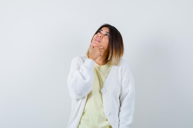 Young woman wearing a white cardigan thinking