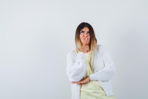 Young woman wearing a white cardigan thinking