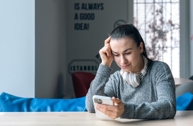 A young woman in white headphones and with a smartphone