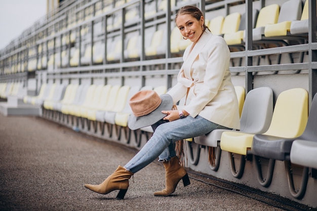 Free photo young woman in white jacket holding hat