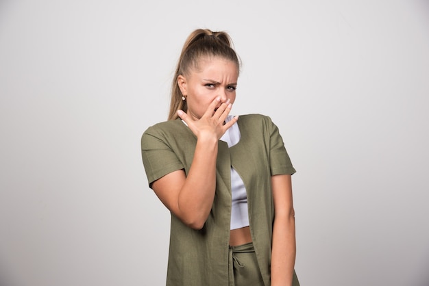 Young woman in white shirt feeling angry on gray wall.