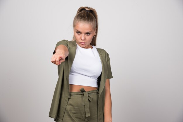 Young woman in white shirt pointing at something.