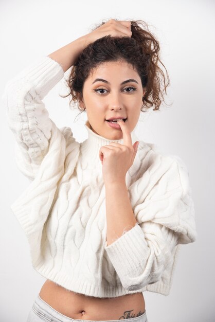 Young woman in white sweater standing over a white wall. High quality photo