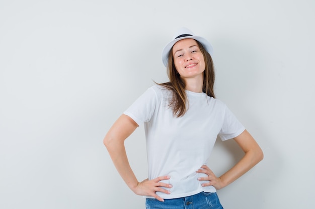 Free Photo young woman in white t-shirt, shorts, hat posing while standing and looking confident.