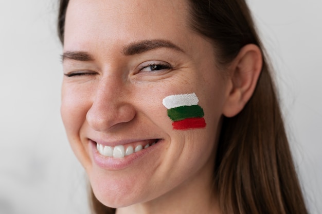 Free photo young woman winking with bulgarian flag painted on cheek