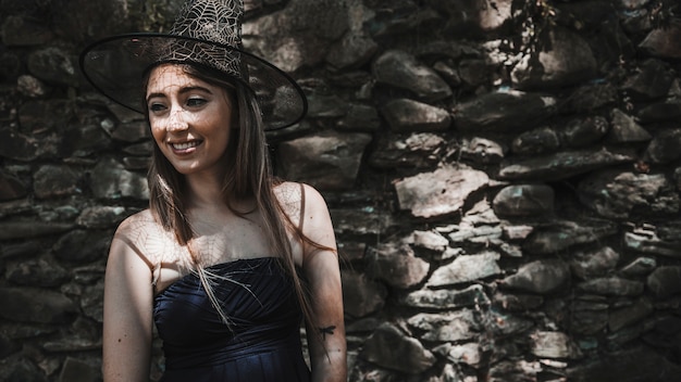 Young woman in witch hat and black dress smiling