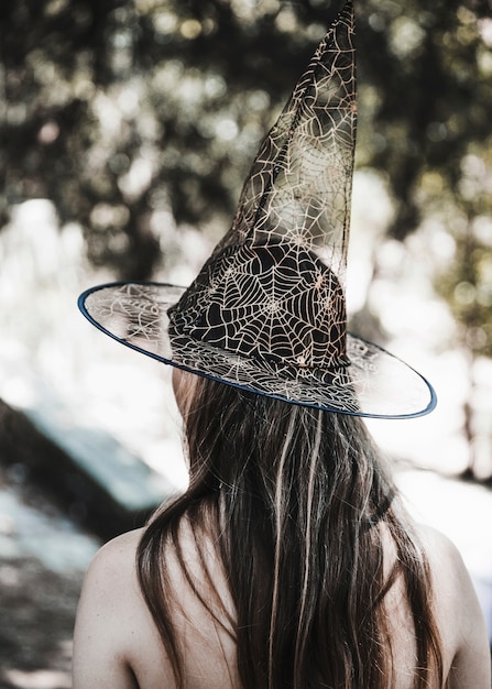 Young woman in witch hat standing in forest