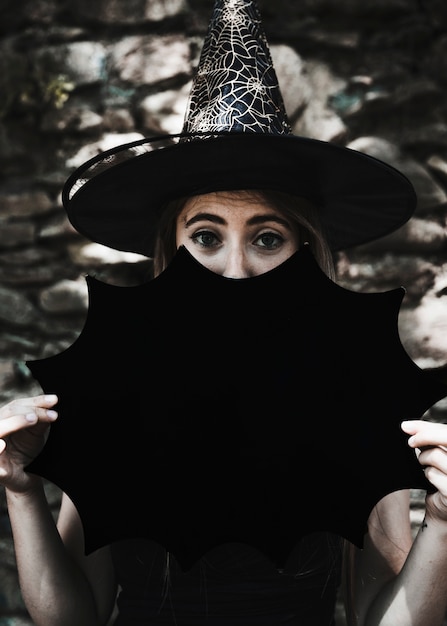 Free photo young woman in witch hat with halloween decoration looking at camera