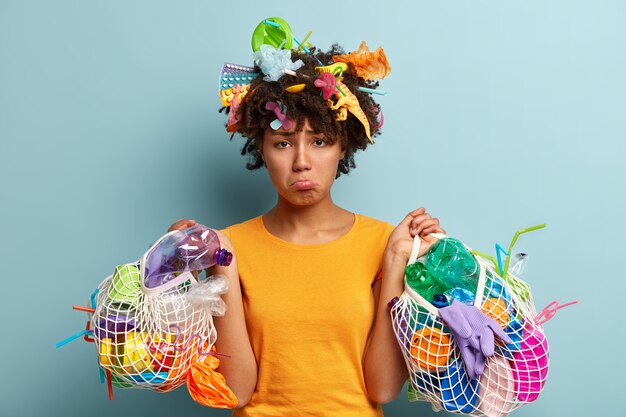 Young woman with Afro haircut holding bag with plastic waste