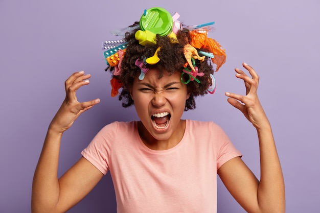 Free photo young woman with afro haircut and plastic waste in her hair