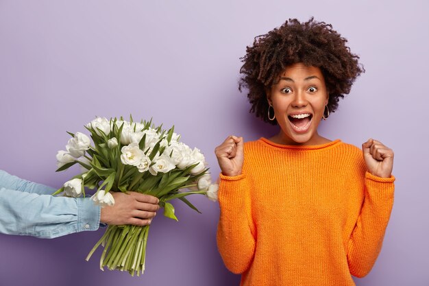 Free photo young woman with afro haircut receiving bouquet of flowers