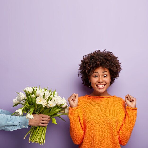 Young woman with Afro haircut receiving bouquet of white flowers