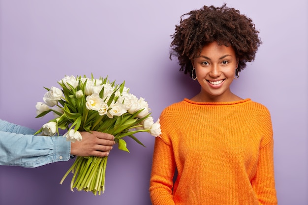 Free photo young woman with afro haircut receiving bouquet of white flowers