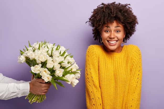 Free photo young woman with afro haircut receiving bouquet of white flowers