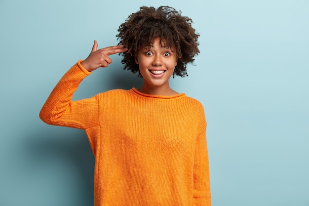 Young woman with Afro haircut wearing orange jumper