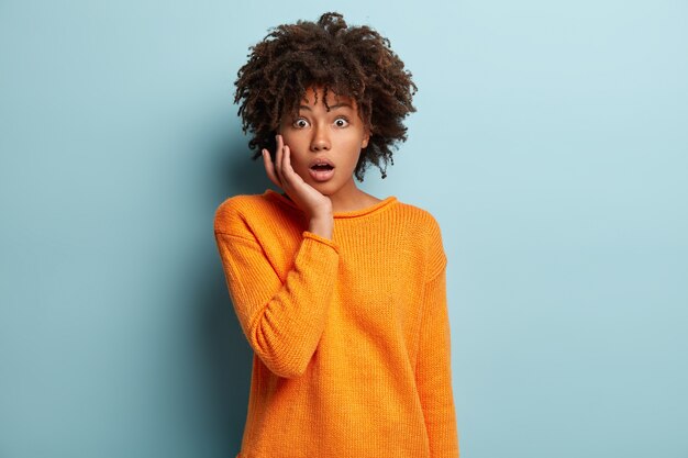 Young woman with Afro haircut wearing orange jumper