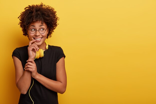 Young woman with Afro haircut and yellow headphones