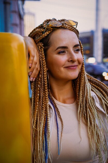 young woman with afro zizi braids and bright makeup in a big city, portrait. zizi braids hairstyles.