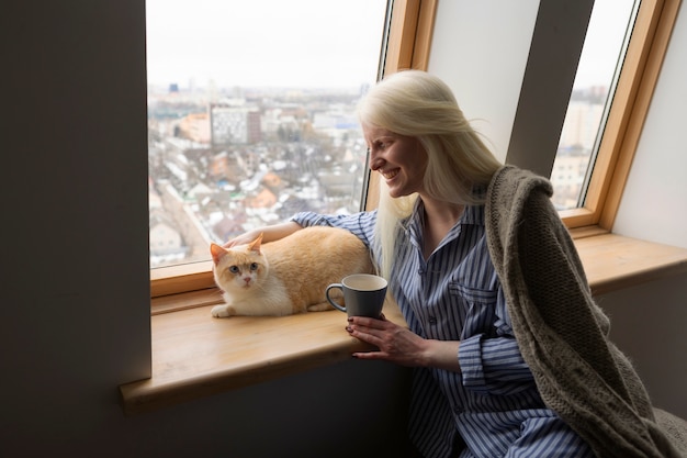 Free Photo young woman with albinism and cat holding coffee cup