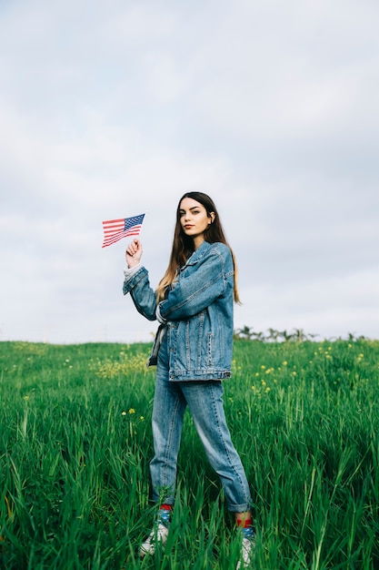 Free photo young woman with american flag staying in field