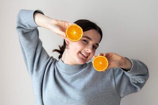 Free Photo a young woman with appetizing halves of an orange on a white background