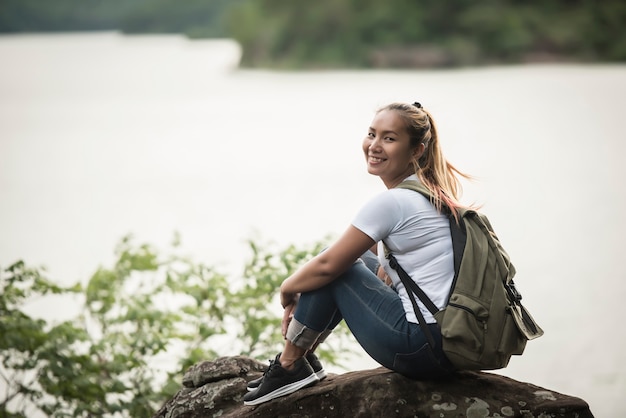 Young woman with backpack sitting enjoy with forest. Travel concept.