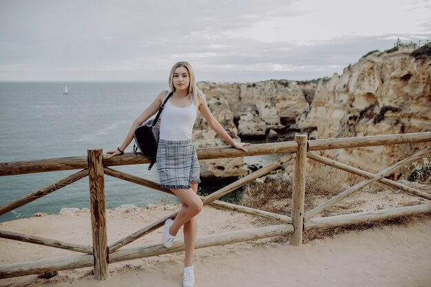 Young woman with backpack Traveler on background beach seascape horizon.