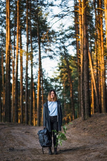 Free photo young woman with backpack and twig