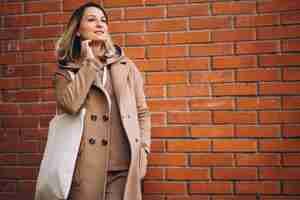 Free photo young woman with bag by the brick wall