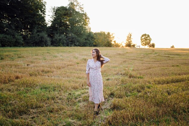 Young woman with beautiful hair posing in field at sunset. Fashion, independence