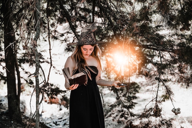 Free photo young woman with book and candle looking down in forest