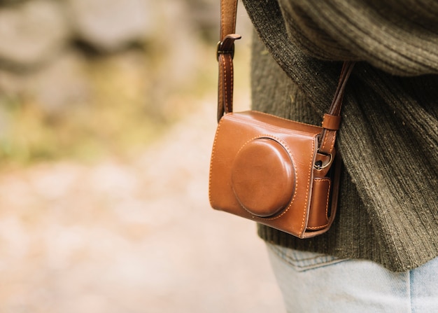 Young woman with camera bag in nature