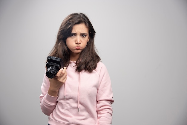 Free photo young woman with camera feeling sad.