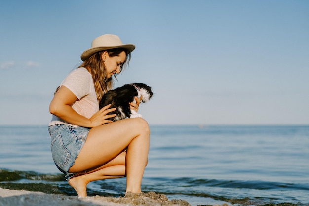 Free photo young woman with a cat on the beach near the sea. travel concept with a pet.