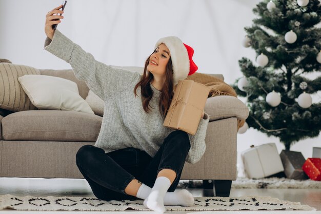 Young woman with christmas presents by the christmas tree