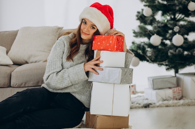 Young woman with christmas presents by the christmas tree