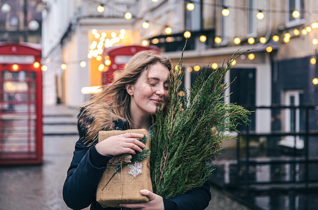 Young woman with a christmas tree and a gift box on a blurred background