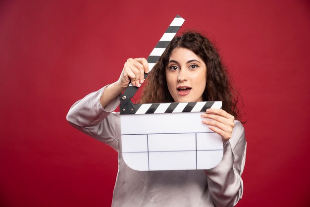 Young woman with clapperboard standing.