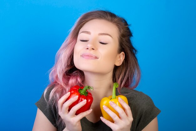 Young woman with closed eyes holds red and yellow peppers