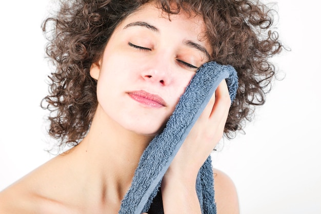 Young woman with closed eyes wiping the body with a towel isolated on white background