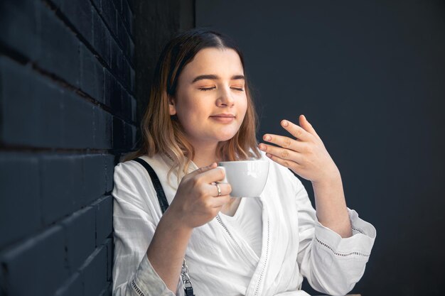 A young woman with coffee cup in black cafe interior