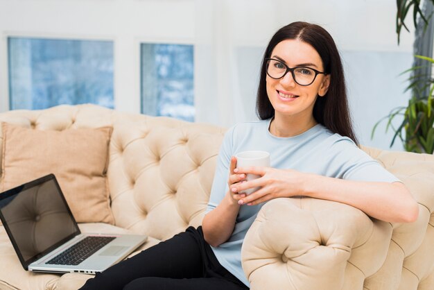 Young woman with coffee cup sitting on couch 