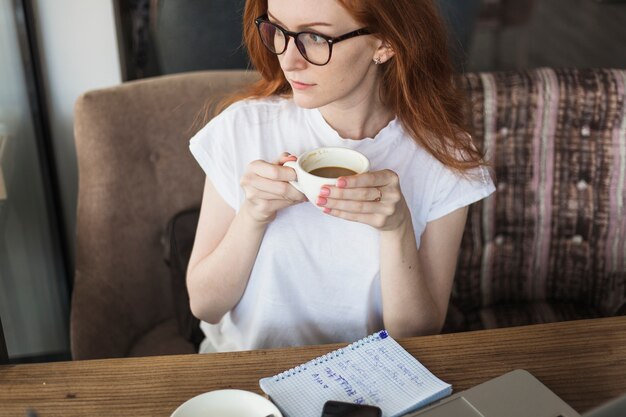 Free Photo young woman with coffee cup at table