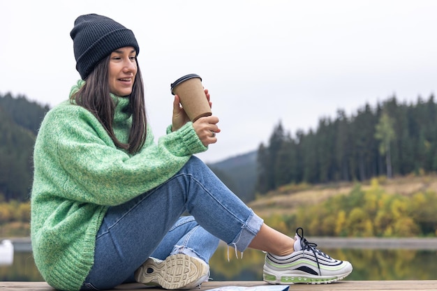 Free Photo a young woman with a cup of coffee and a map on a background of mountains