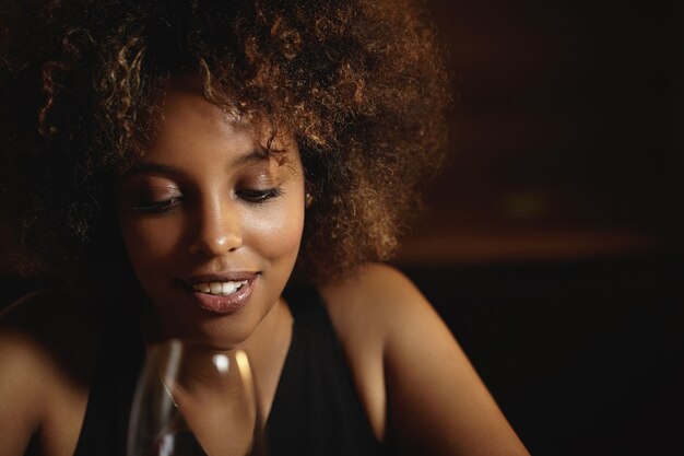 Young woman with curly hair and a glass of red wine