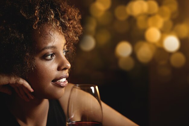 Young woman with curly hair and a glass of red wine