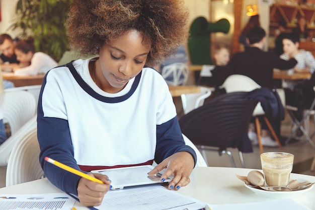 Young woman with curly hair using tablet in cafe