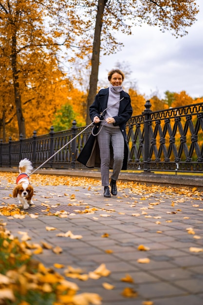 A young woman with a dog walks in the autumn park