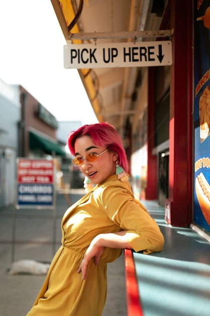 Free photo young woman with dyed hair near shop